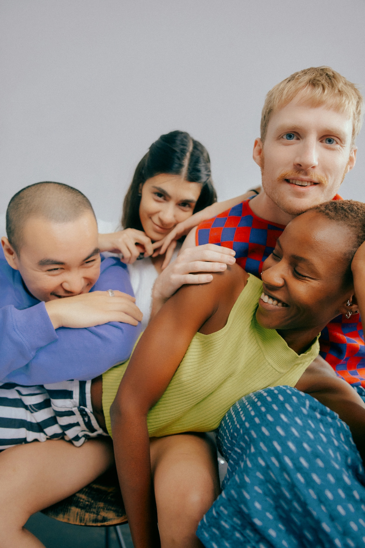 Friends laughing in a soft pile, joyful and intimate